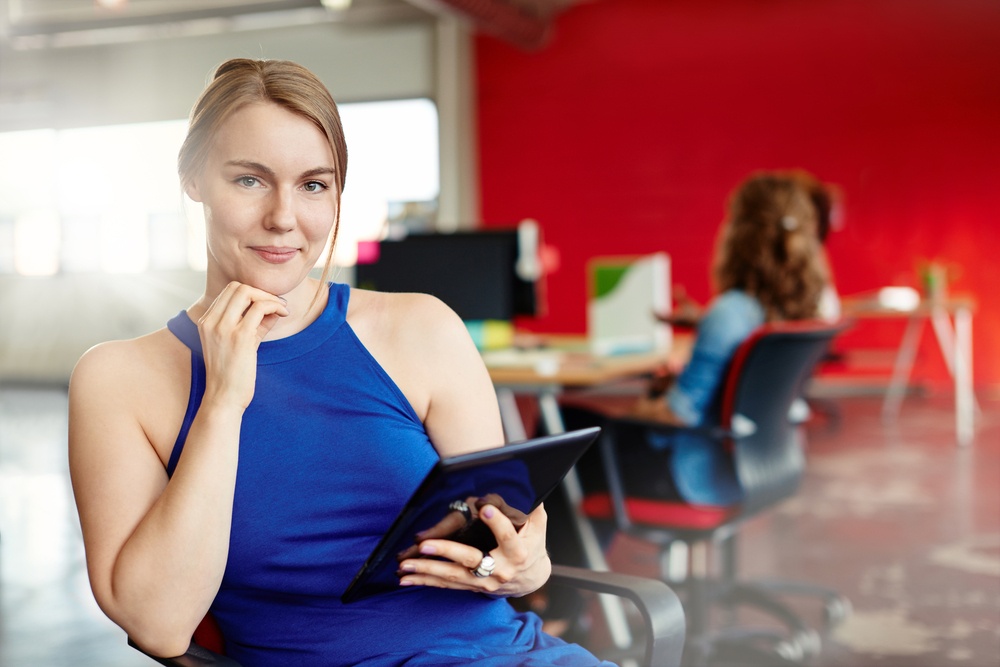 Confident female designer working on a digital tablet in red creative office space-2